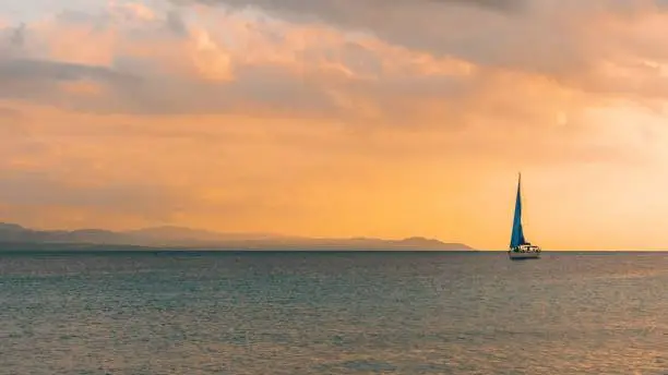 An image of a sailboat cruising leisurely on a tranquil ocean on an overcast day