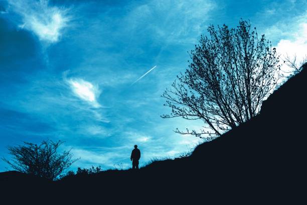 istock a person standing on a hill with trees and the sky behind 1492968887