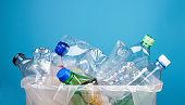 Waste plastic bottles in recycle bin on blue background