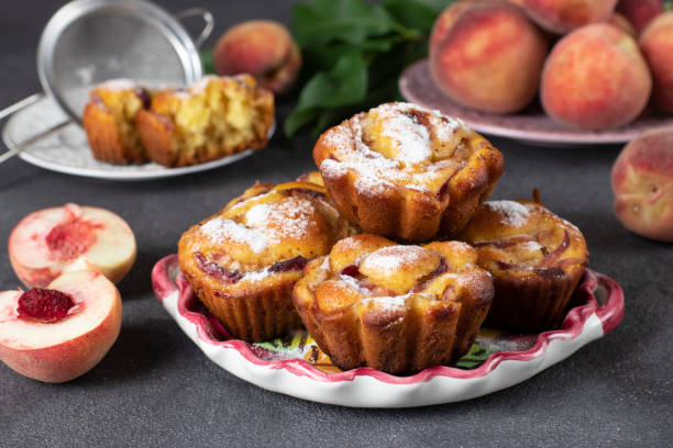 Homemade tasty muffins with peaches on plate on gray background stock photo