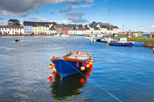 Boat in Galway Bay in front of old Galway Town and it's pastel buildings.