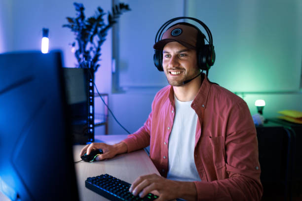 istock Young handsome man with hat and headset playing video games on desktop PC at home 1492971838