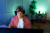 Young handsome man with hat and headset playing video games on desktop PC at home