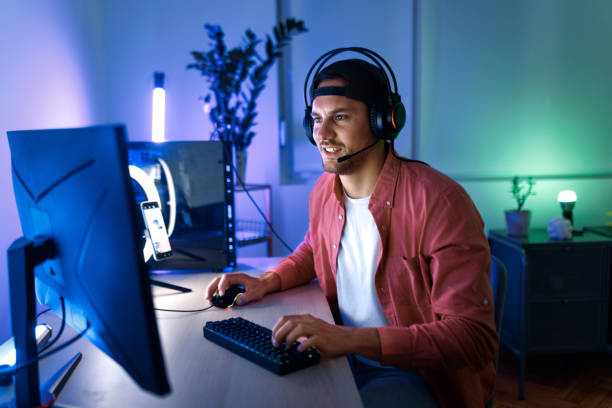 istock Smiling handsome man playing video games on desktop PC at home 1492971842