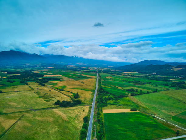 istock Aerial view from drone flight over different agricultural fields and the road to the mountains with clouds 1492974570