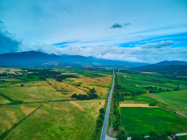 istock Aerial view from drone flight over different agricultural fields and the road to the mountains with clouds 1492974894