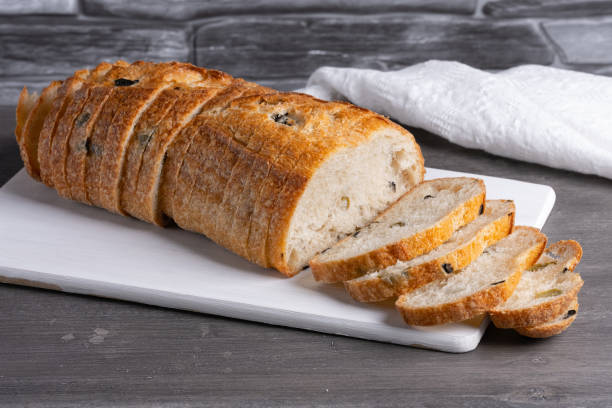 istock Bread with olives on a white cutting board on a gray table 1492975555
