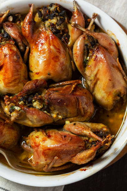 istock Baked quail stuffed with mushrooms, eggs and bread in a ceramic form on a wooden table. 1492985941