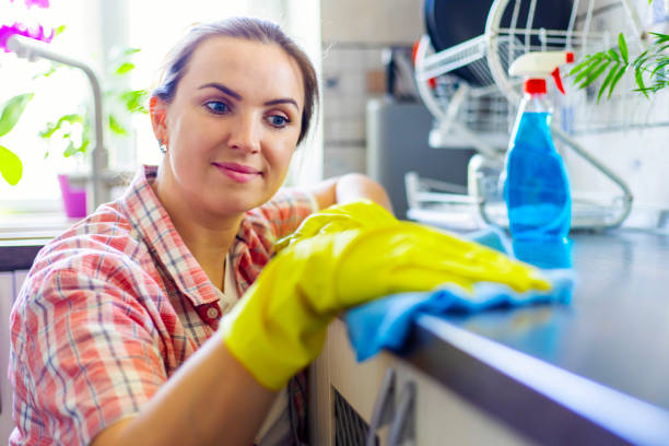 istock Housewife in yellow gloves wipes dust using spray detergent and rag 1492989932