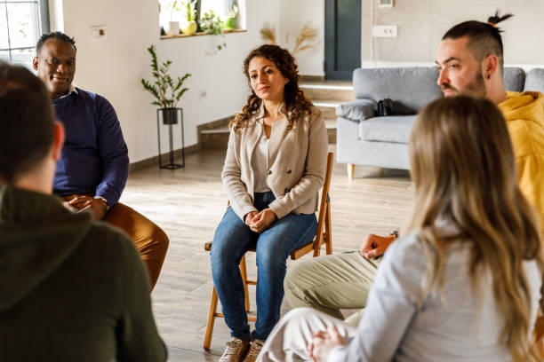 istock Group of people sitting in circle, talking during group therapy 1492991902