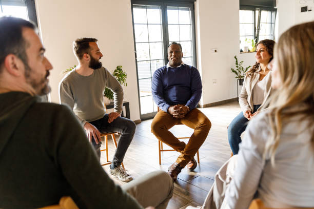 istock Group of people sitting in circle, talking during group therapy 1492991974
