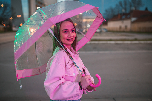 Beautiful woman walking around the city holding an umbrella during a rainy night