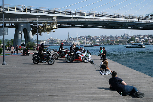 Istanbul, Turkey - May 21, 2023: A group of motorcyclists on the Golden Horn, on the coast of Istanbul, with the metro bridge in the background.
