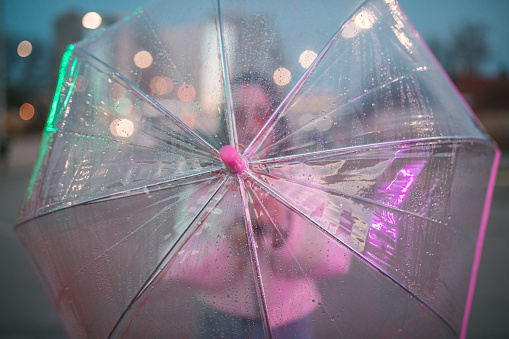 Close-up shot of a rain-soaked umbrella held by an unrecognizable woman