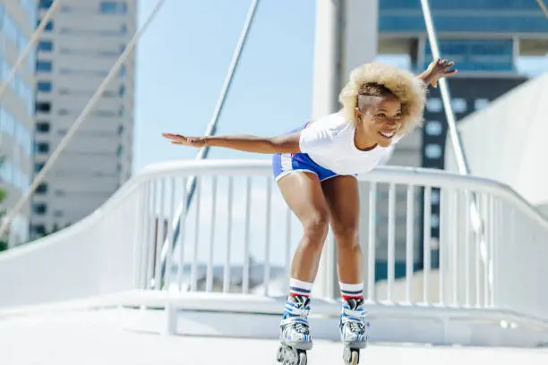 Woman with afro hairstyle rollerblading on sunny day