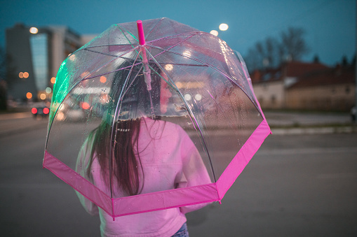 Beautiful woman walking around the city holding an umbrella during a rainy night