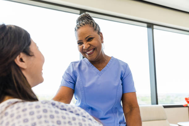 Female patient and female nurse smile at each other stock photo