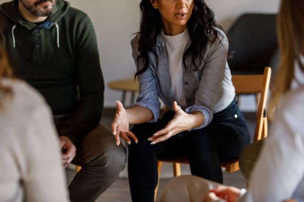 Anxious young woman sharing her struggles with her peers during a group therapy session stock photo