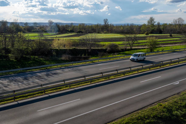 white modern delivery small shipment cargo courier van moving fast on motorway road to city urban suburb. - mini van fotos imagens e fotografias de stock