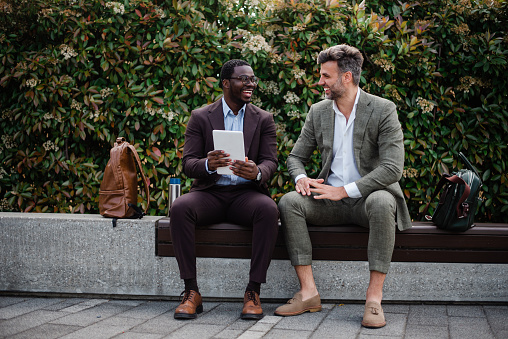 Two middle age businessmen co-workers talking outside at business district during successful deal.