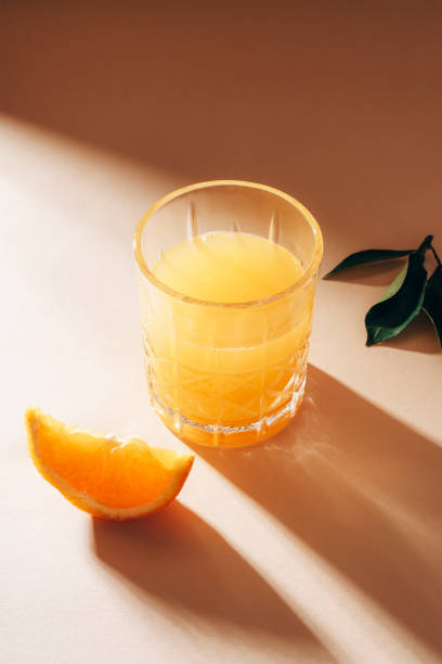 istock Orange juice on beige table with long shadows. Healthy drink. Closeup 1492998952