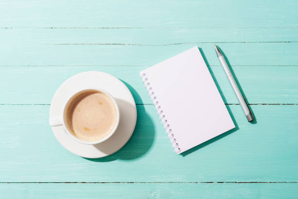 istock A cup of coffee, notepad and pen on turquoise blue table in sunlight. Top view, flat lay, mockup 1492999033