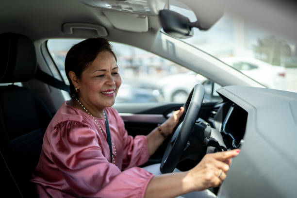 Mature woman using car GPS navigation or changing radio music inside a car Mature woman using car GPS navigation or changing radio music inside her car old person listening to radio stock pictures, royalty-free photos & images