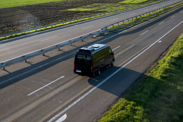 black modern delivery small shipment cargo courier van moving fast on motorway road to city urban suburb. - van moving van commercial land vehicle truck imagens e fotografias de stock