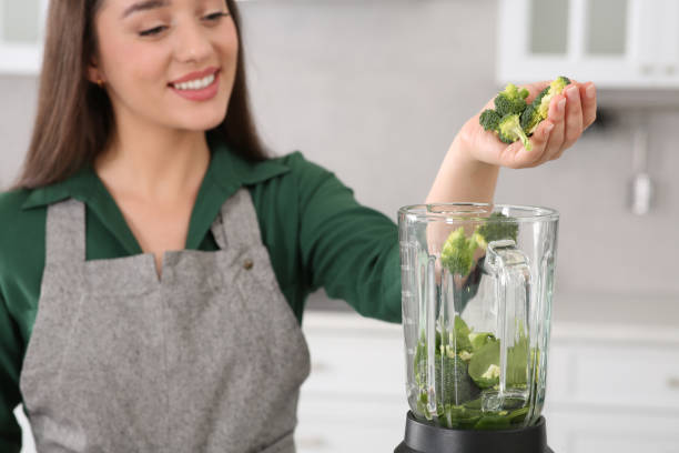 istock Woman adding broccoli into blender with ingredients for smoothie in kitchen, focus on hand 1493008551
