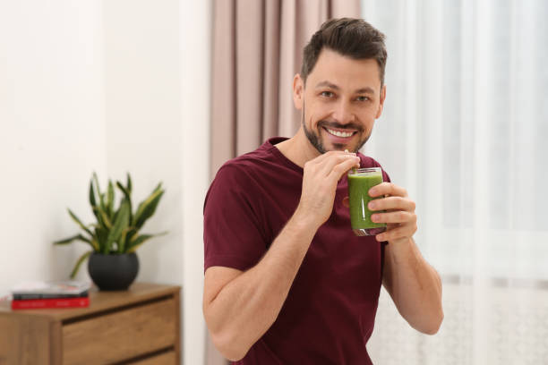 istock Happy man drinking delicious fresh smoothie at home 1493008558