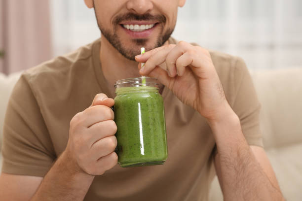 istock Happy man drinking delicious fresh smoothie indoors, closeup 1493008565