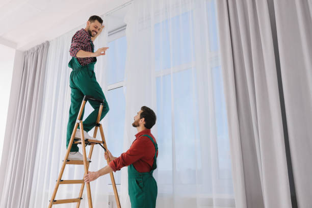 istock Workers in uniform hanging window curtain indoors, low angle view 1493009237