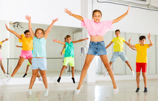 Group of cheerful tweens having fun and jumping during modern dances class