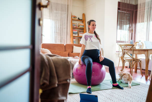 беременная женщина занимается с мячом для пилатеса в домашних условиях - human pregnancy prenatal care relaxation exercise ball стоковые фото и изображения