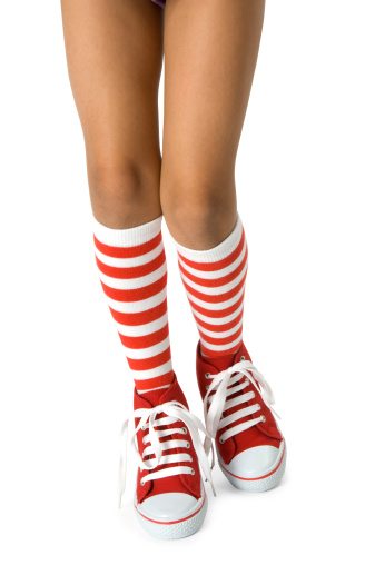 Young girls legs wearing long red striped socks with red shoes, walking on a white background. Clipping path included.