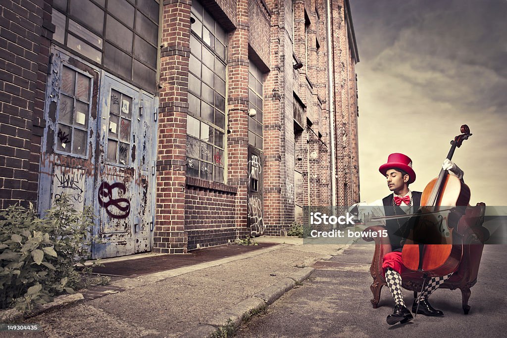 Old-fashioned cellist Young man in funny clothes playing the cello on a city street Adult Stock Photo