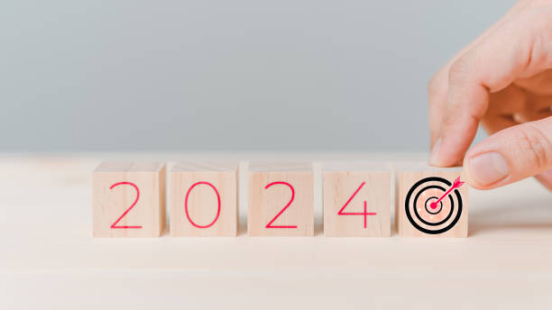 Hand putting wooden cube block with goal icon and 2024 icon on table background. Start new year 2024 with goal plan for work, action plan, strategy, new year business vision.