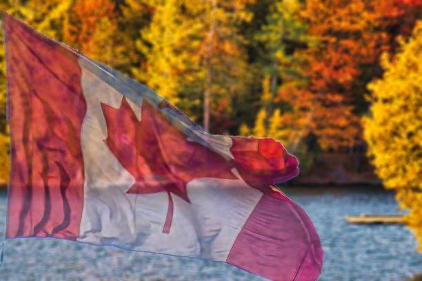 istock canadian maple leaf flag and fall colors lake 1493053933