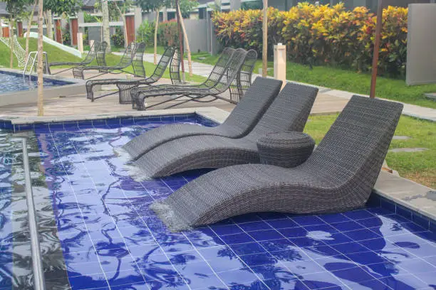 seats made of rattan to relax and sunbathe by the swimming pool in an exotic villa