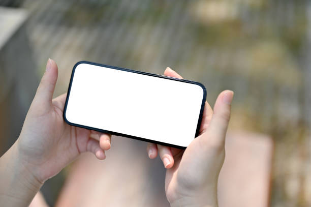 istock A smartphone white screen mockup in a horizontal position in a woman's hands 1493068486