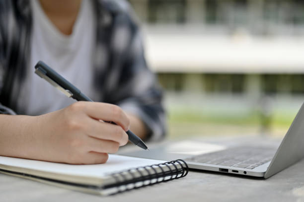 istock Cropped image of a female college student doing homework in a campus park 1493068505