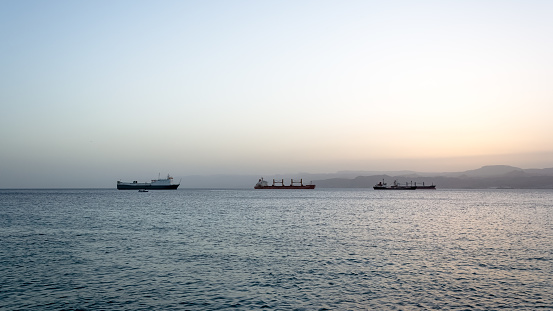 Aqaba, Jordan – September 2014 – This stunning photograph captures the beauty of a beautiful sunny afternoon at Aqaba beach, which serves as Jordan's window on the Red Sea. In the background, you can see the impressive Flagpole and port facilities, adding to the picturesque coastal scenery.