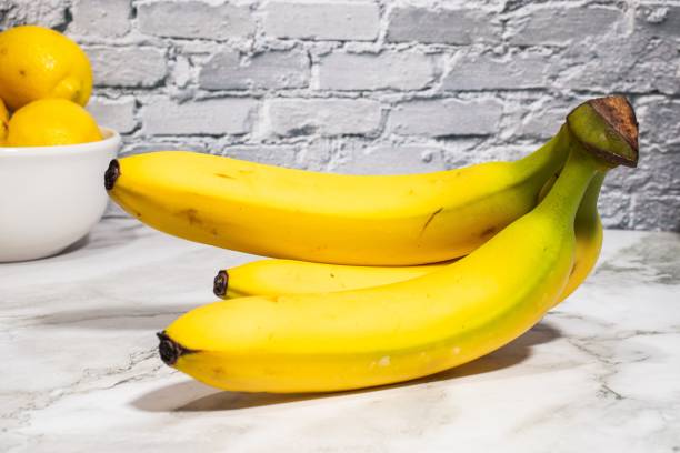 istock White table with three yellow bananas and one bowl of fresh lemons 1493074043