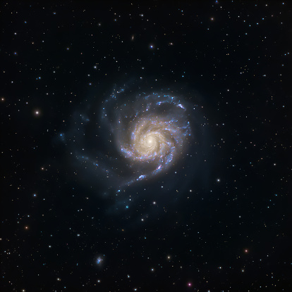Grand spiral Galaxy Messier 101 in the constellation Ursa Major. Blue oxygen and pink hydrogen gas visible with colorful foreground stars.
