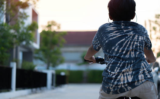 Little Asian boy riding bicycle at summer day on the road in early morning. Back view,  selective focus.