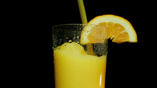 Pouring Orange Juice in Freshly Washed Glass With Orange Slice on Glass