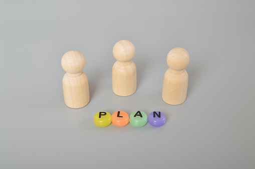 Wooden figures with text plan. Project management time planning in the business realm, symbolized by the interplay of gears and the diligent guidance of a businessman. Implementing business process management and automated workflow