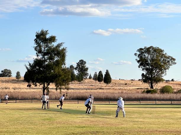 uomini australiani che giocano a cricket nel parco locale - sport of cricket village cricket player english culture foto e immagini stock