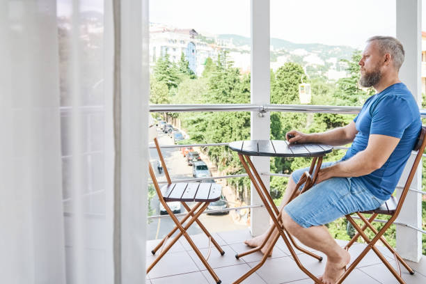istock Bearded man sitting at table on balcony enjoys vacation 1493097194