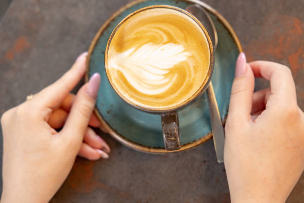 istock Female hands with a cappuccino cup in a cafe 1493099995